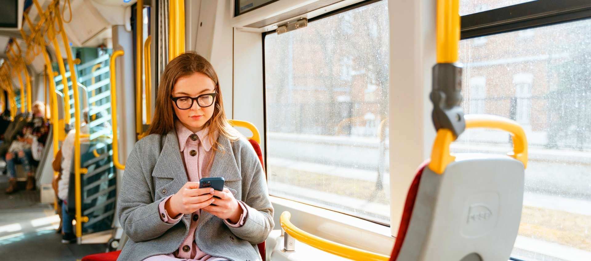 Woman sitting on bus looking at her phone.