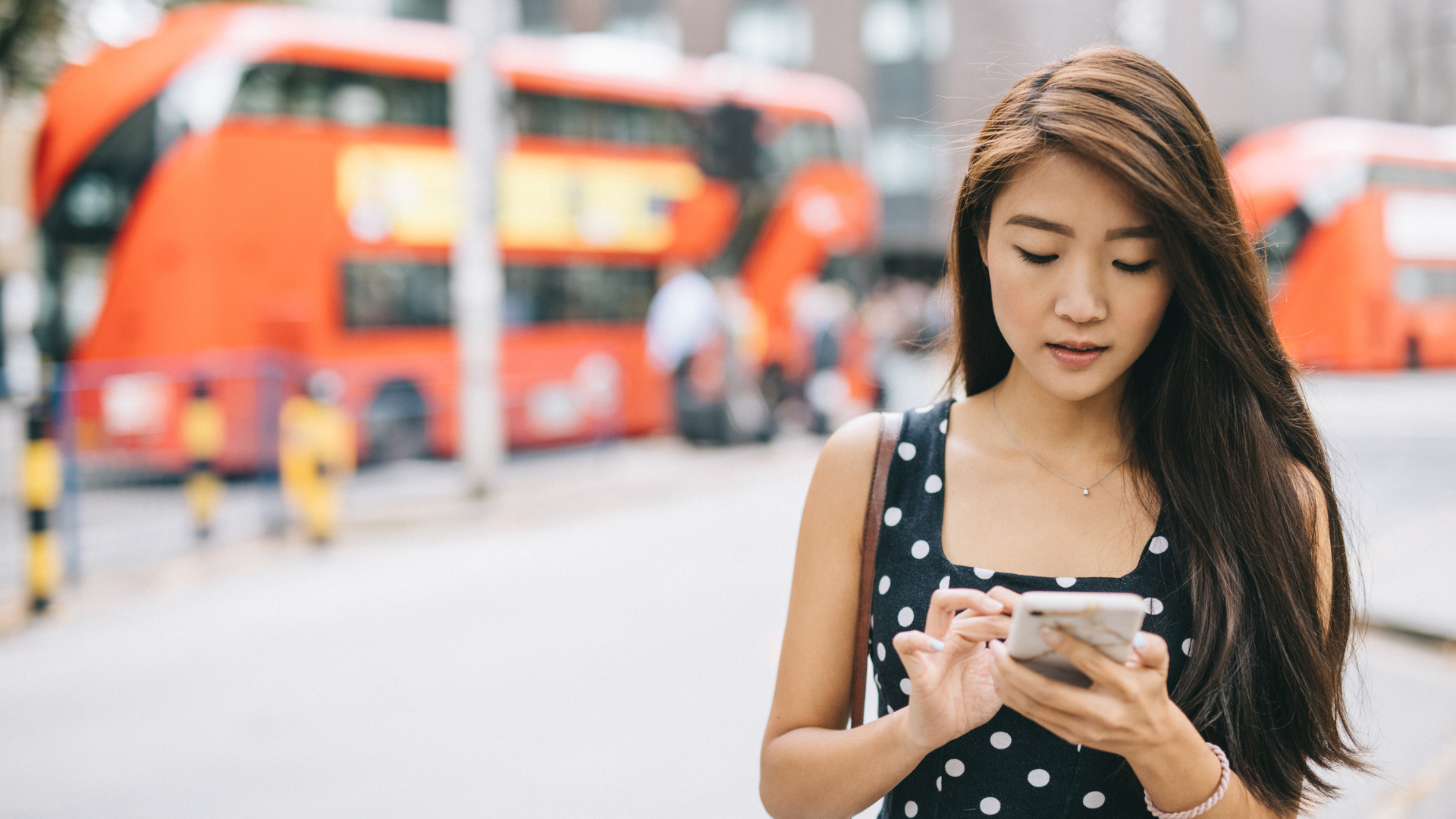A woman looking at her phone, cityscape in background. 