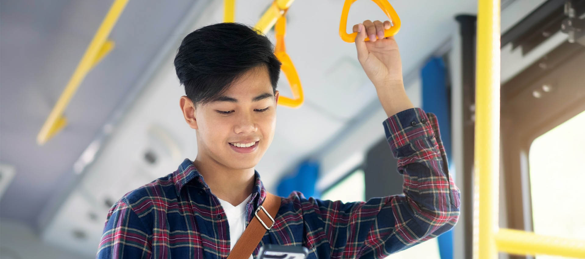 Man riding a bus while looking at phone. 