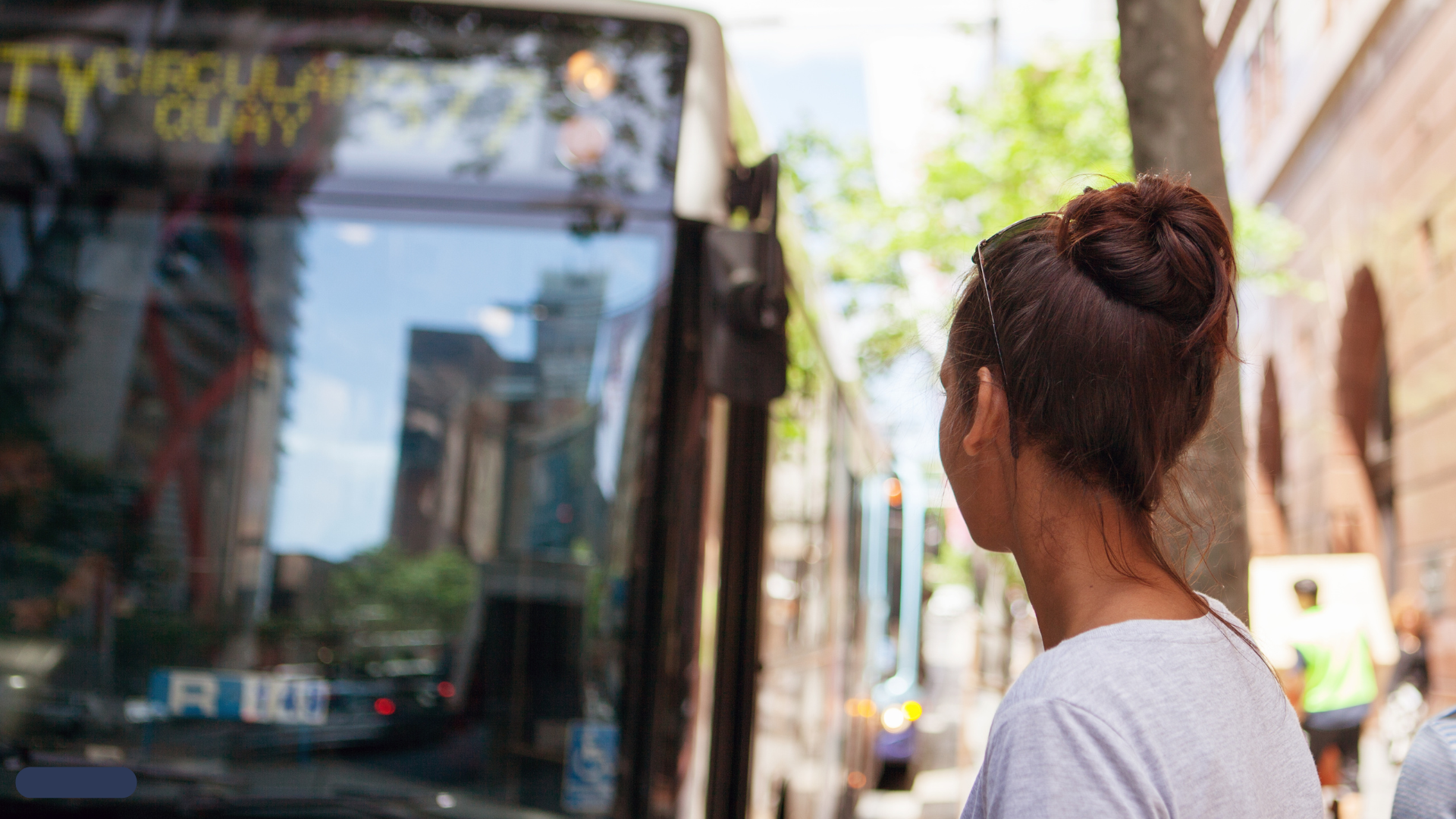 Bus arriving to pick up woman at stop.