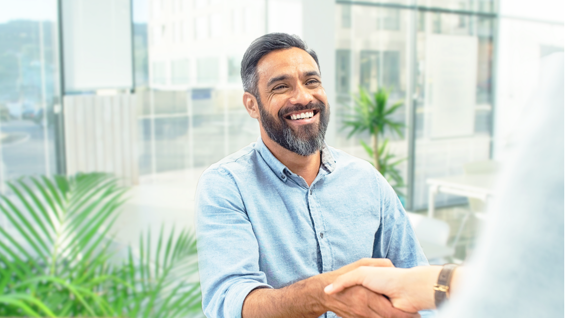 Smiling man shaking hands with someone off screen.